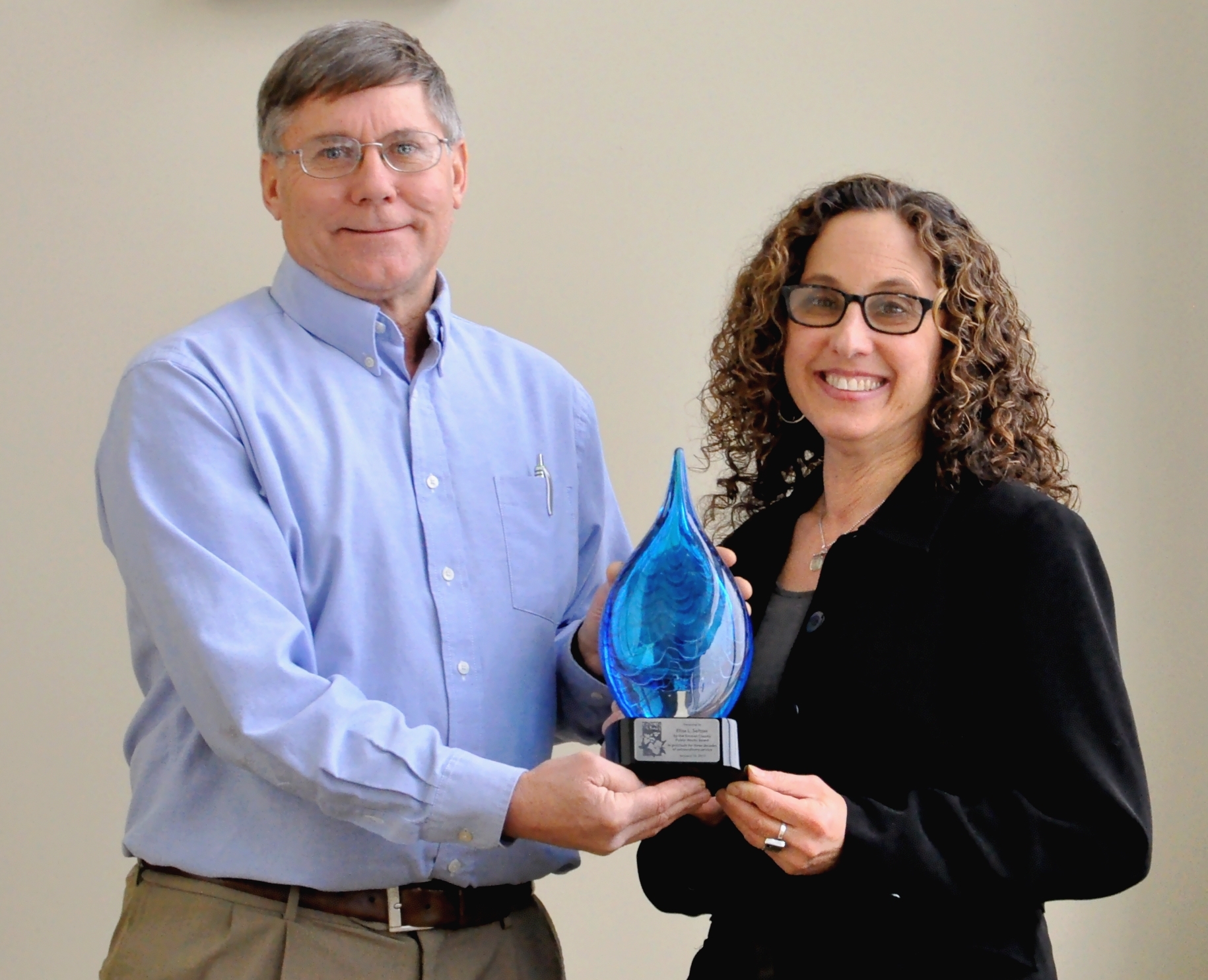Photo of Denny Keiser presenting sculpture to Elisa at January DPW Board Meeting